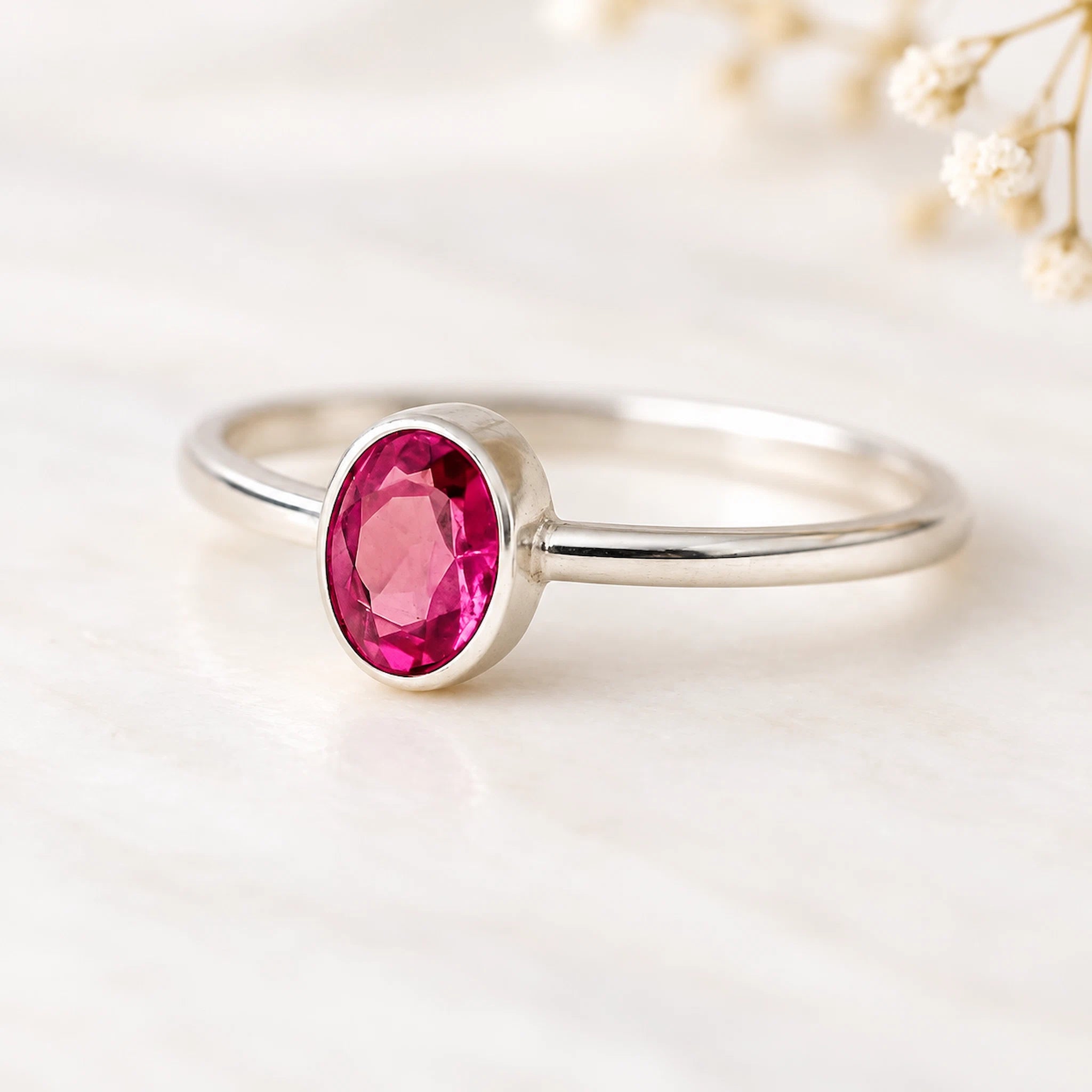 Silver ring with a pink gemstone on a light background