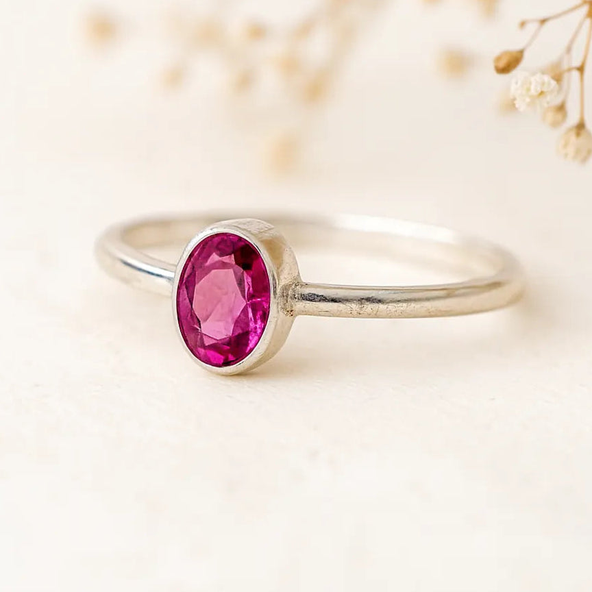 Silver ring with a pink gemstone on a light background