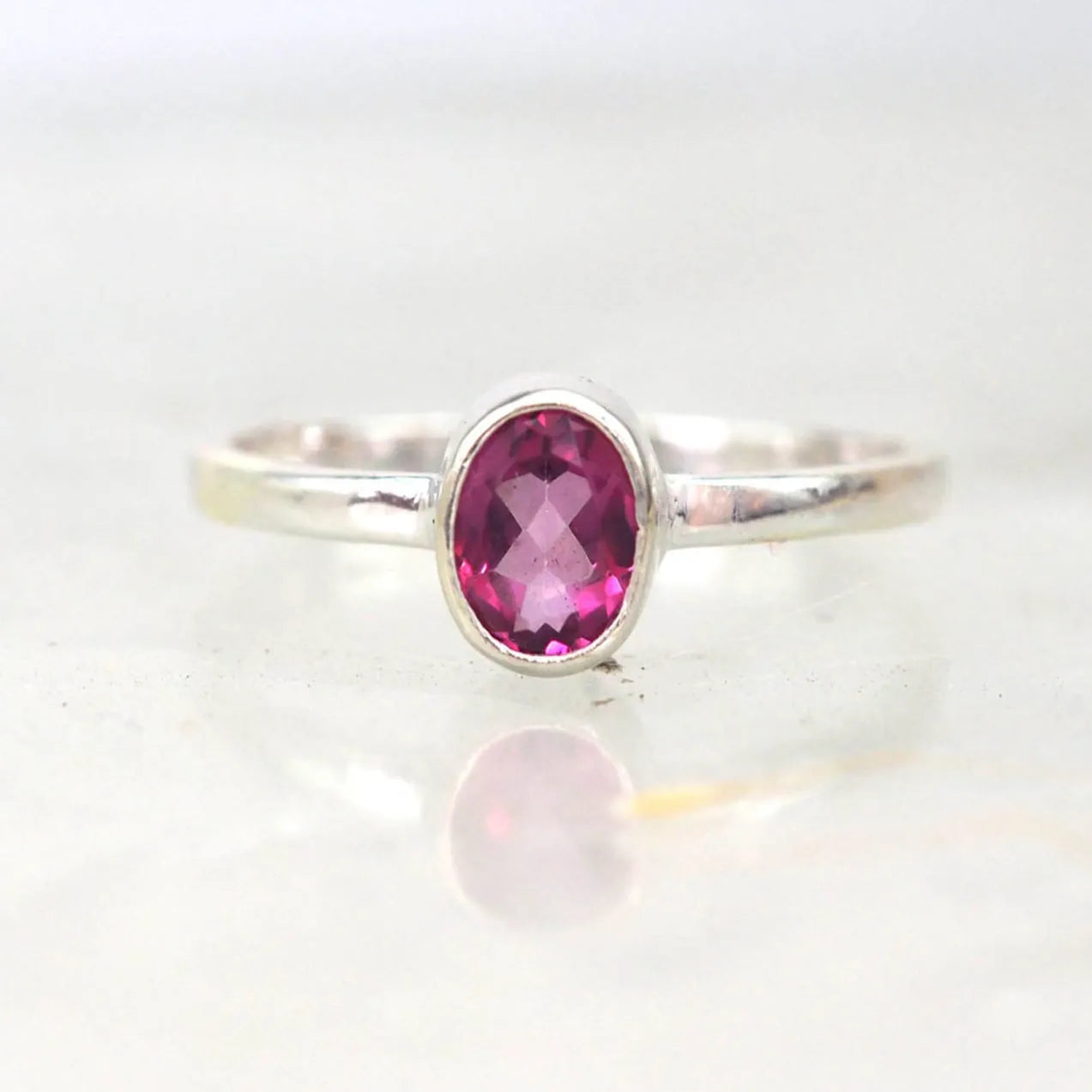 Silver ring with a pink gemstone on a white background