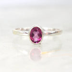 Silver ring with a pink gemstone on a white background