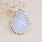 Teardrop-shaped gemstone with silver setting on a neutral background
