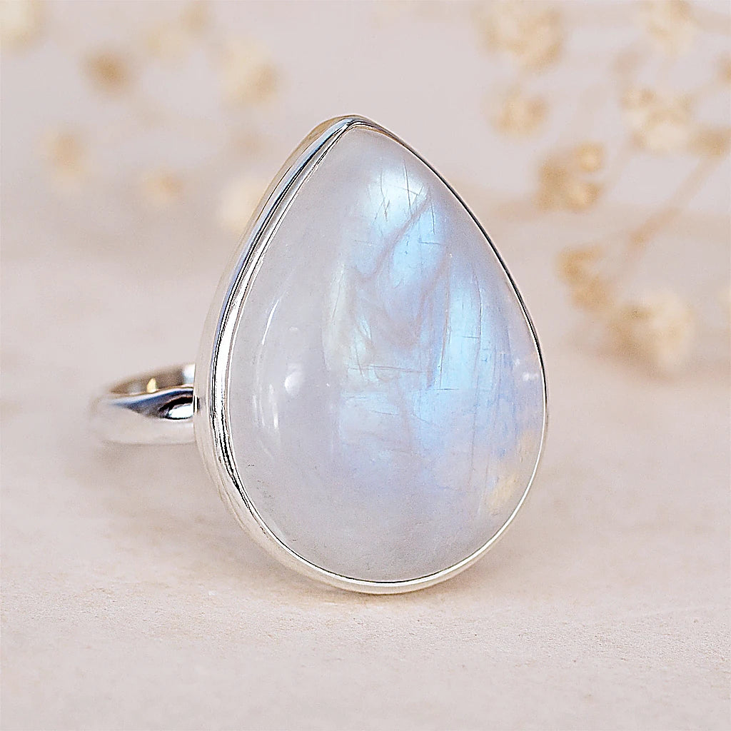Teardrop-shaped gemstone ring on a soft beige background