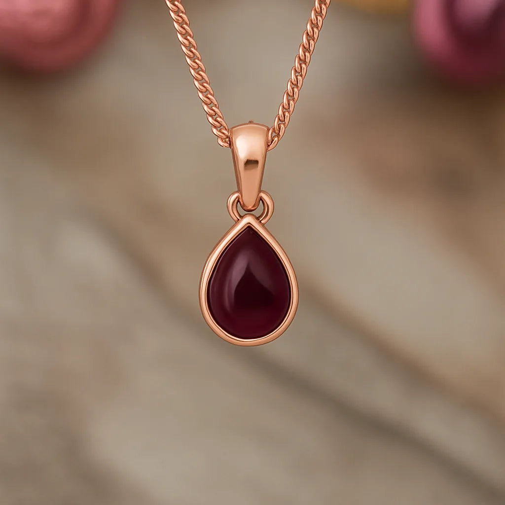 Rose gold pendant with a red gemstone on a soft brown background