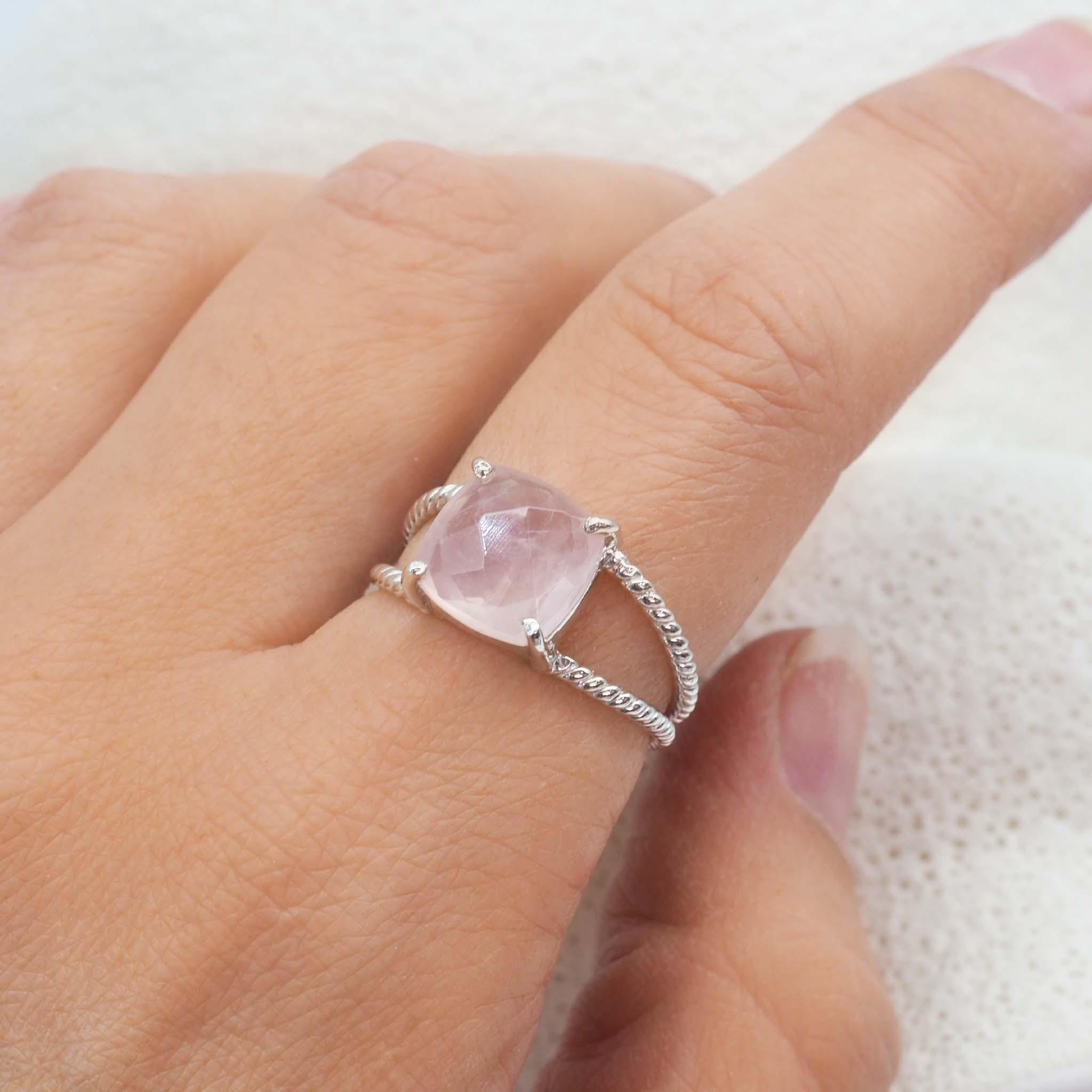 finger wearing a sterling silver double band ring with claw set, faceted natural rose quartz gemstone