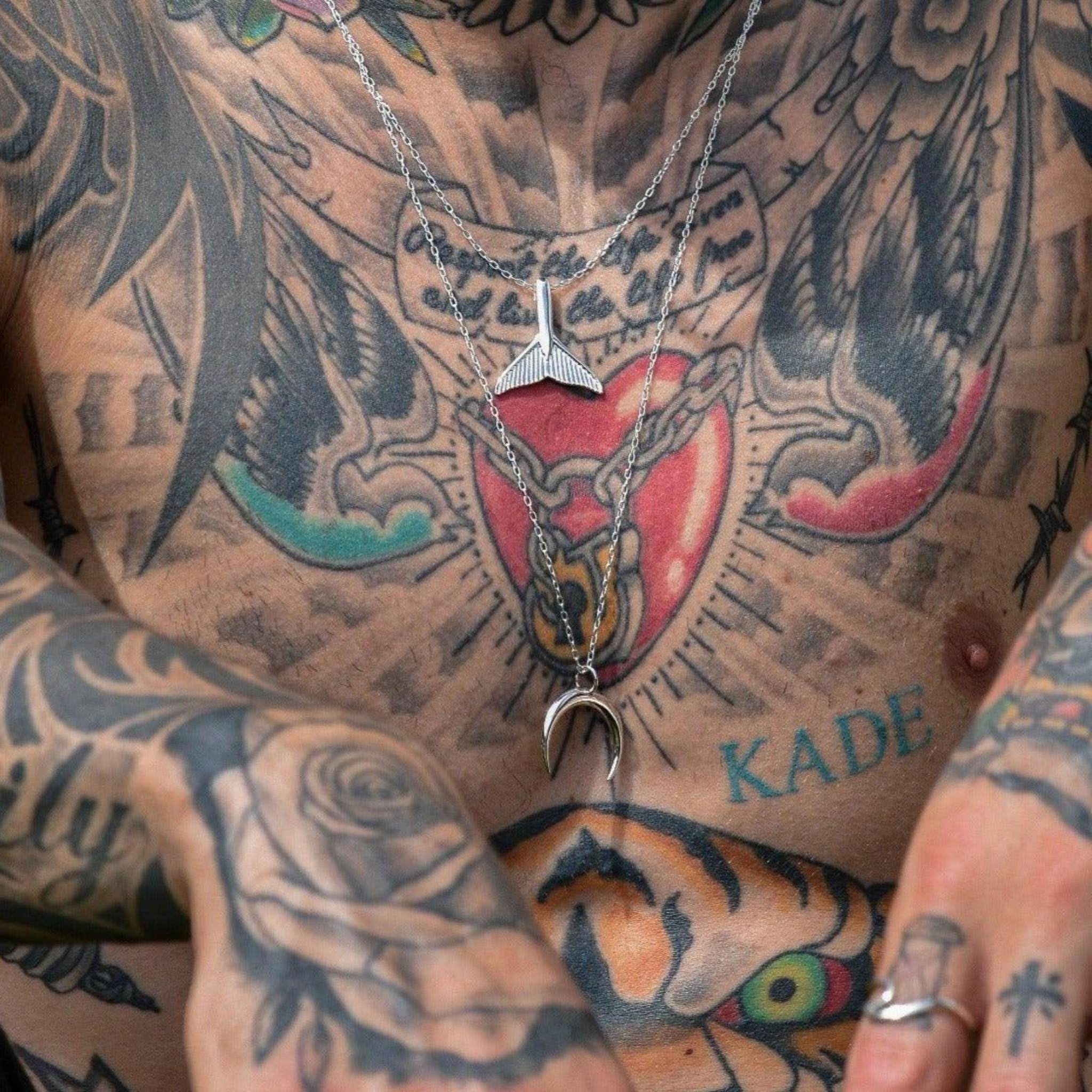 tattooed man wearing sterling silver whale tail necklace and sterling silver half moon necklace