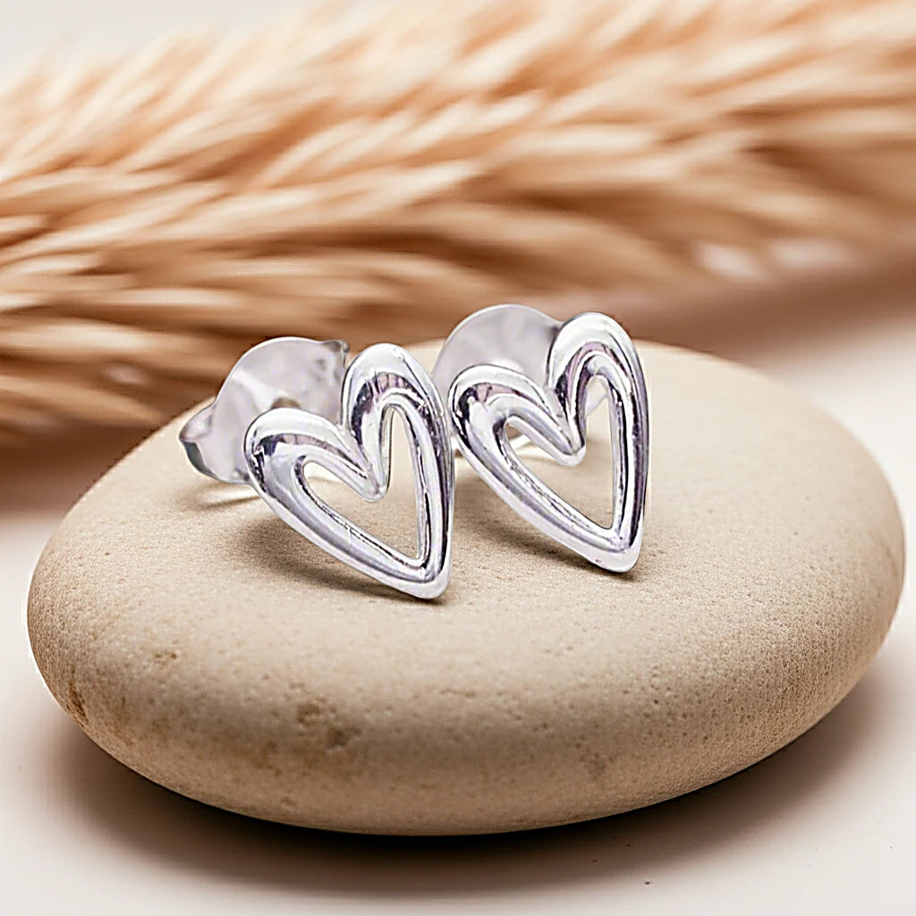 Silver heart-shaped earrings on a stone with a blurred natural background