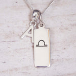 Silver necklace with a pendant featuring an 'A' and a symbol on a light wooden background