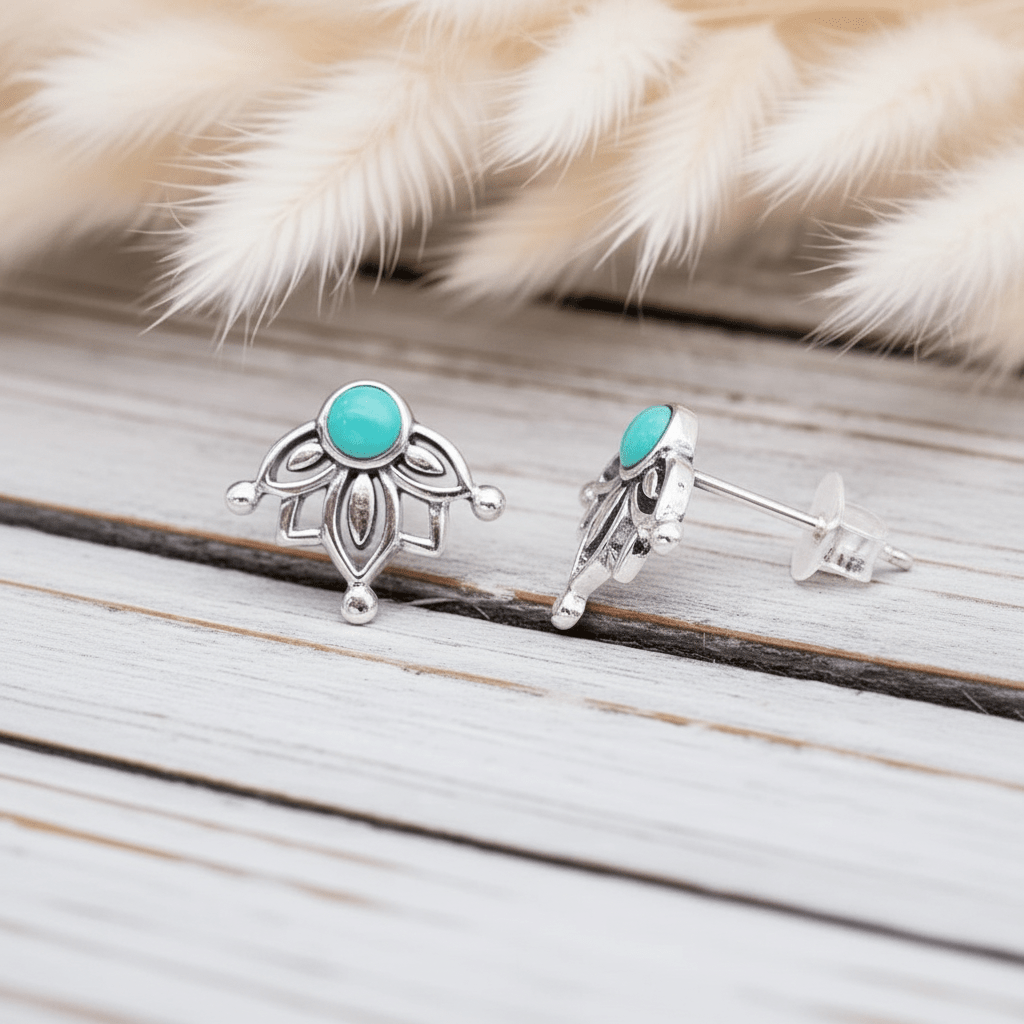 Silver earrings with turquoise stones on a wooden surface with fur in the background
