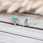 Silver earrings with turquoise stones on a wooden surface with fur in the background