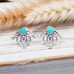 Silver earrings with turquoise stones on a wooden surface