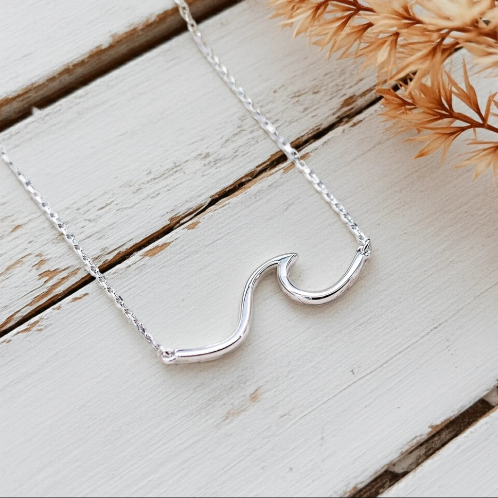 Silver necklace with a unique pendant on a wooden surface