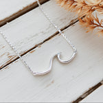 Silver necklace with a unique pendant on a wooden surface