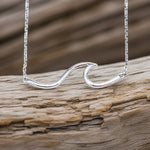 sterling Silver wave-shaped necklace on a wooden surface by indie and harper australian jewellery