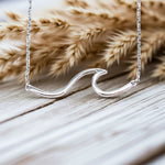 sterling Silver wave-shaped necklace on a wooden surface with dried pampas grass - indie and harper australian jewellery