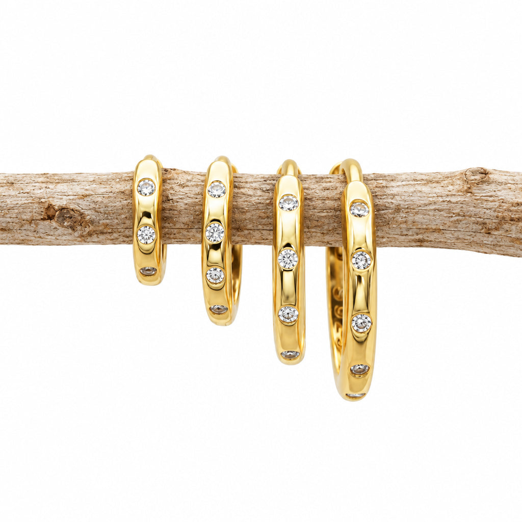 Gold CZ hoop earrings in four sizes laid out side by side