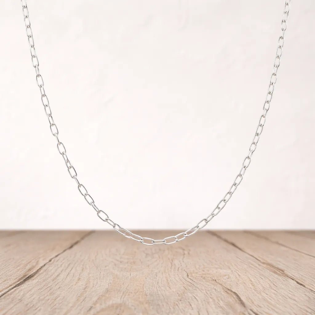 Silver chain necklace on a wooden surface with a light background