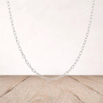 Silver chain necklace on a wooden surface with a light background