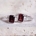 indie and harper silver silver rings with red gemstones on a textured surface
