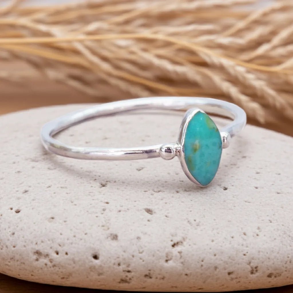 Silver ring with a turquoise stone on a pebble