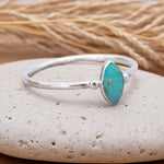 Silver ring with a turquoise stone on a pebble