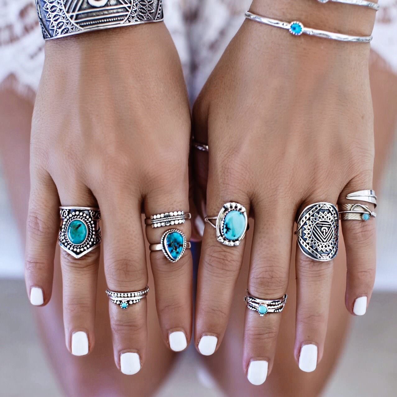 Close-up of hands wearing multiple silver rings with turquoise stones on a blurred background