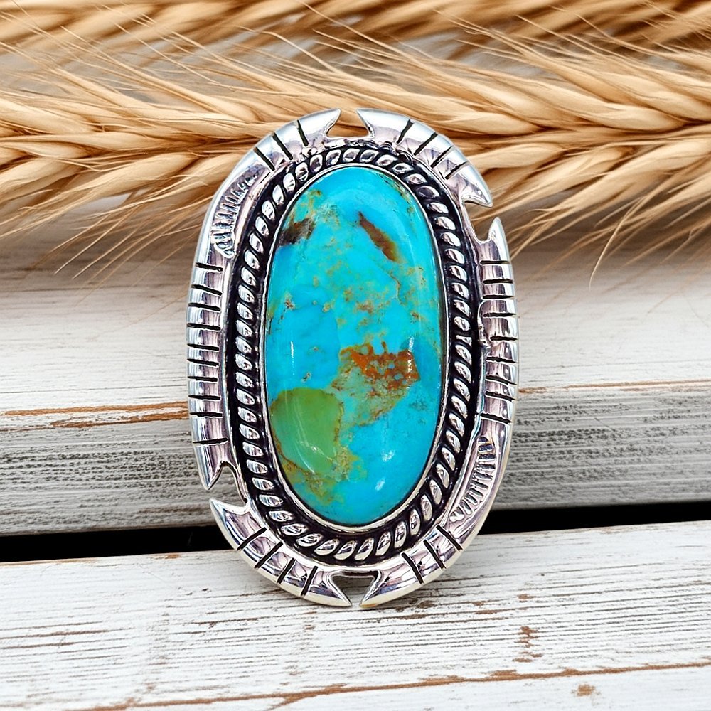Silver ring with a turquoise stone on a wooden surface