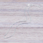 dainty italian sterling silver fine chain anklet laying on a light wooden surface