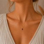 gold january birthstone garnet necklace featuring a dainty teardrop natural garnet pendant, being worn on a model