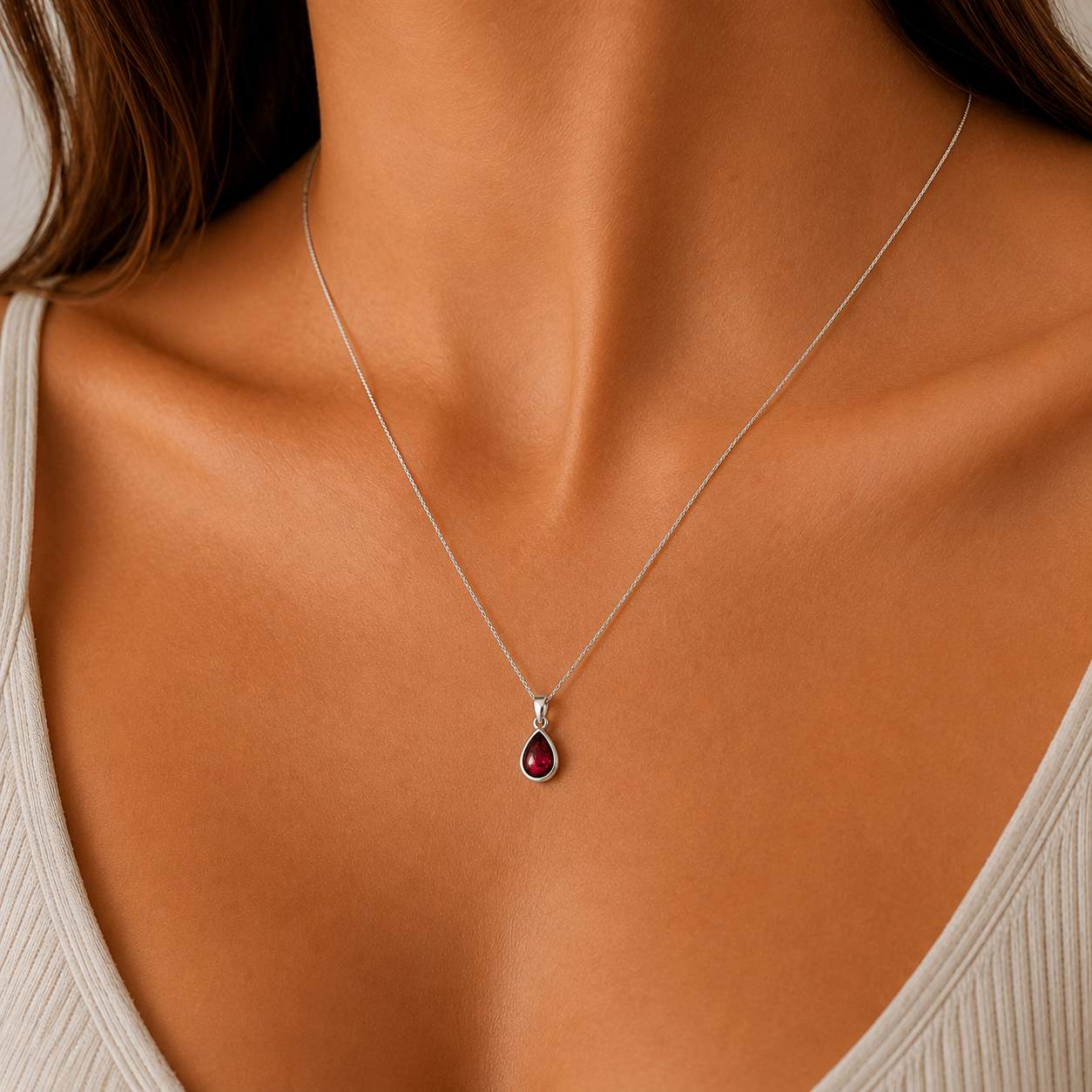 sterling silver january birthstone garnet necklace being worn. dainty pear-shaped natural cabochon bezel-set garnet