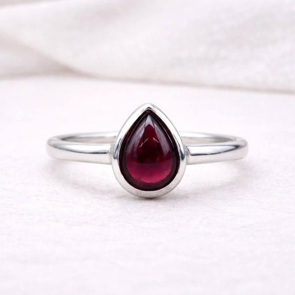 Sterling Silver ring with a teardrop-shaped red natural garnet gemstone on a white background