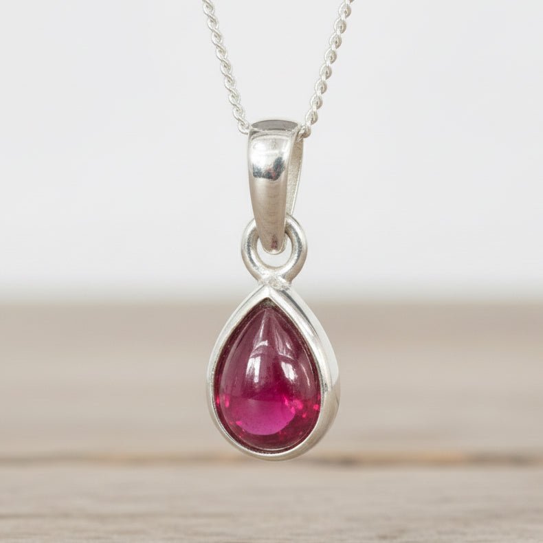 Sterling Silver pendant with a teardrop-shaped red ruby gemstone on a white background