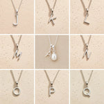 Collection of silver necklaces with initial pendant J to Q on a beige background as personalised letter options to add to a June Birthstone Mother of Pearl Necklace.