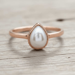 Pearl ring with rose gold setting on a white background