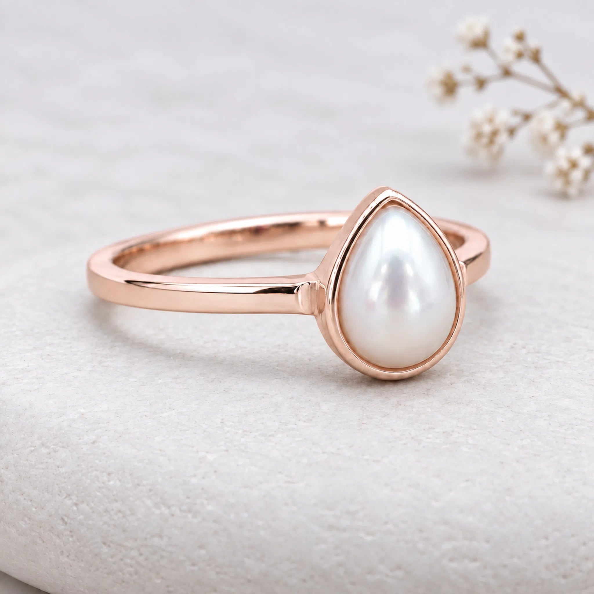Dainty rose gold june birthstone ring featuring a smooth, pear-shaped mother of pearl gemstone in a sleek bezel setting.