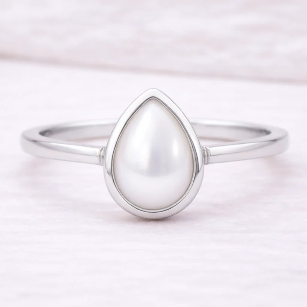 Natural mother of pearl June birthstone ring with a pear-shaped stone in a smooth bezel setting, on a slender sterling silver band.