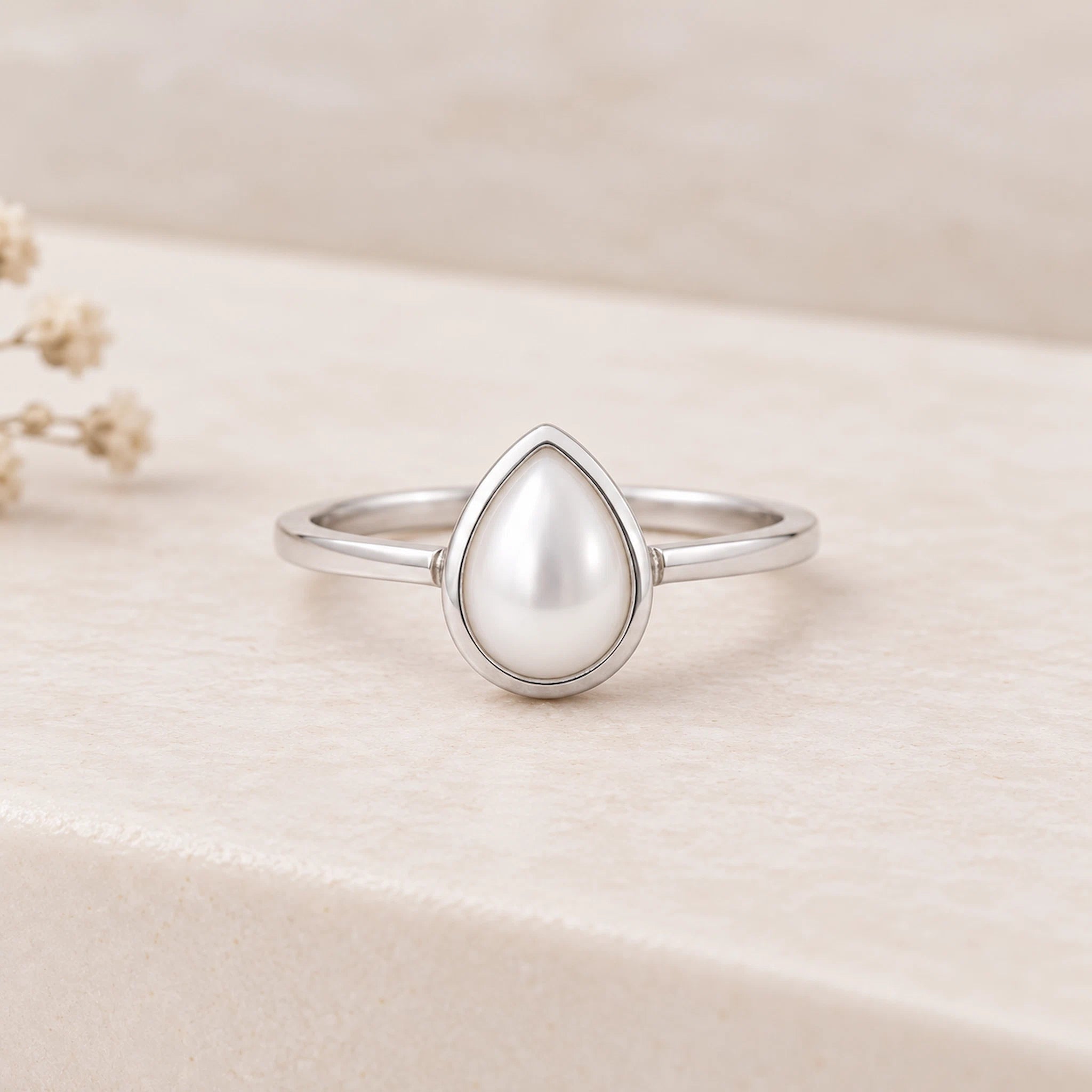 Natural mother of pearl June birthstone ring with a pear-shaped stone in a smooth bezel setting, on a slender sterling silver band.