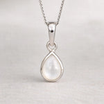 Silver teardrop pendant on a chain against a light gray background
