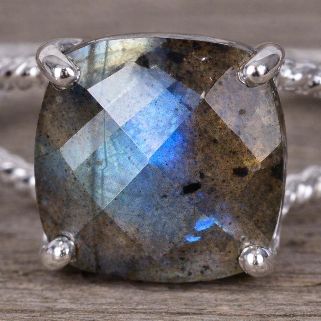 Silver ring with a large, faceted natural labradorite gemstone on a wooden surface