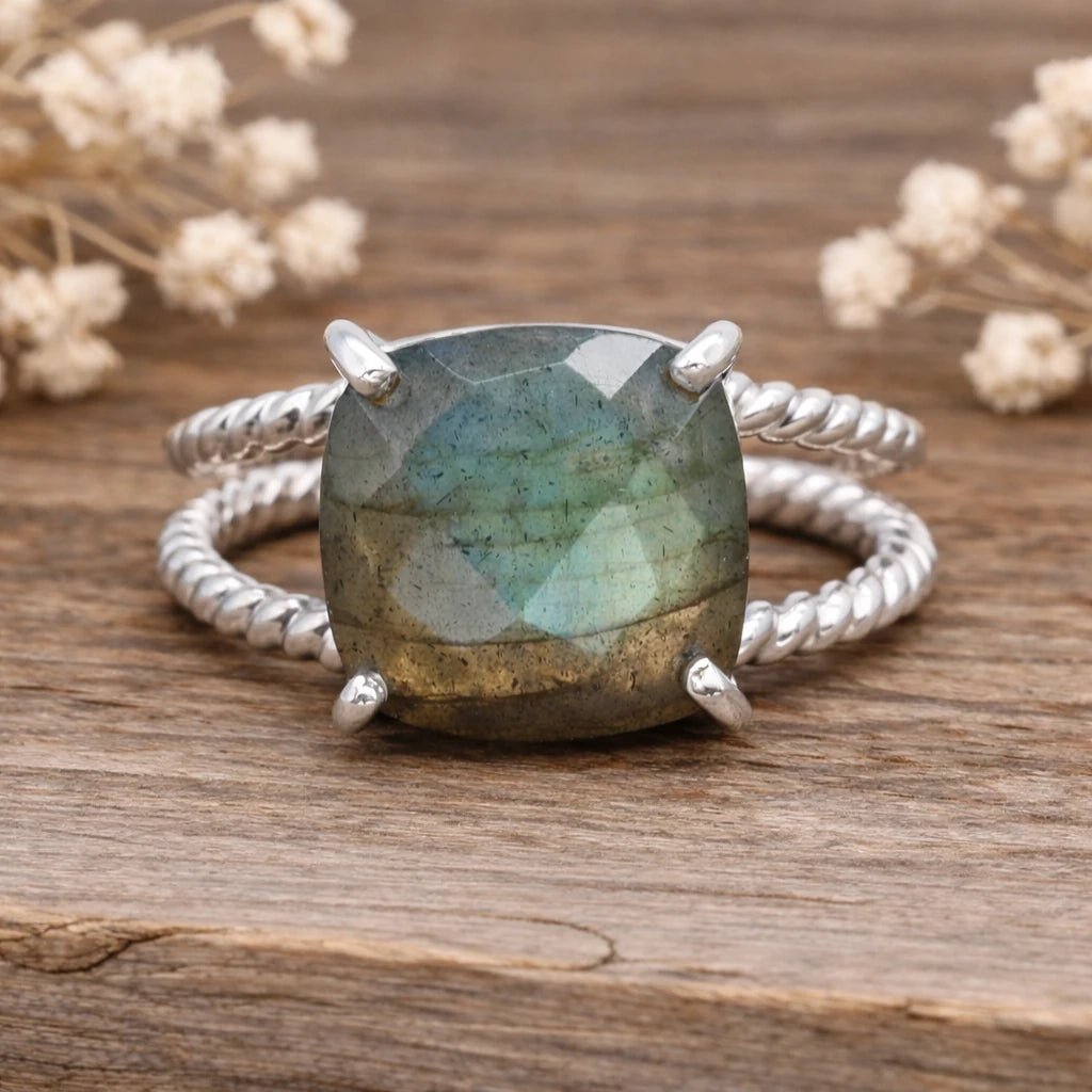sterling Silver ring with a large natural labradorite gemstone on a wooden surface with dried flowers.