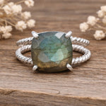 sterling Silver ring with a large natural labradorite gemstone on a wooden surface with dried flowers.