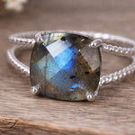 Silver ring with a large labradorite stone on a wooden surface