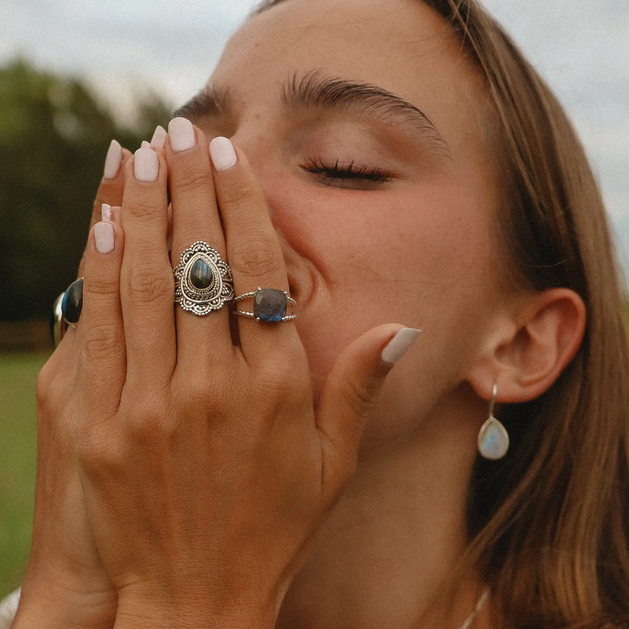 woman with her hands over her face wearing two sterling silver rings with labradorite stones - boho jewellery Australia 