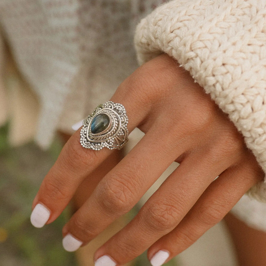 woman wearing a white sweater and a sterling silver ring with a teardrop labradorite stone and silver detailing around it - boho jewellery Australia 