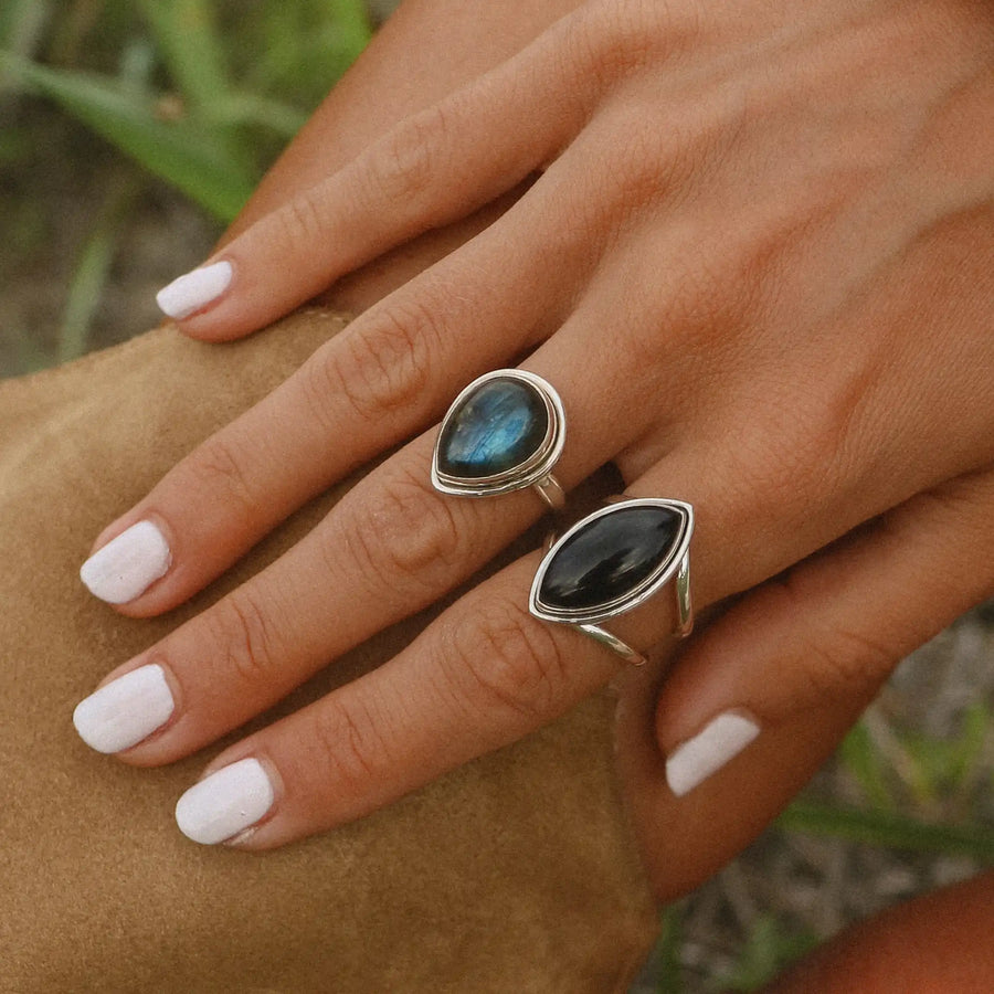 woman wearing two sterling silver rings, one with a labradorite stone and the other with an onyx stone