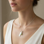 sterling silver Necklace with a leo zodiac pendant and august birthstone peridot pendant worn by a person