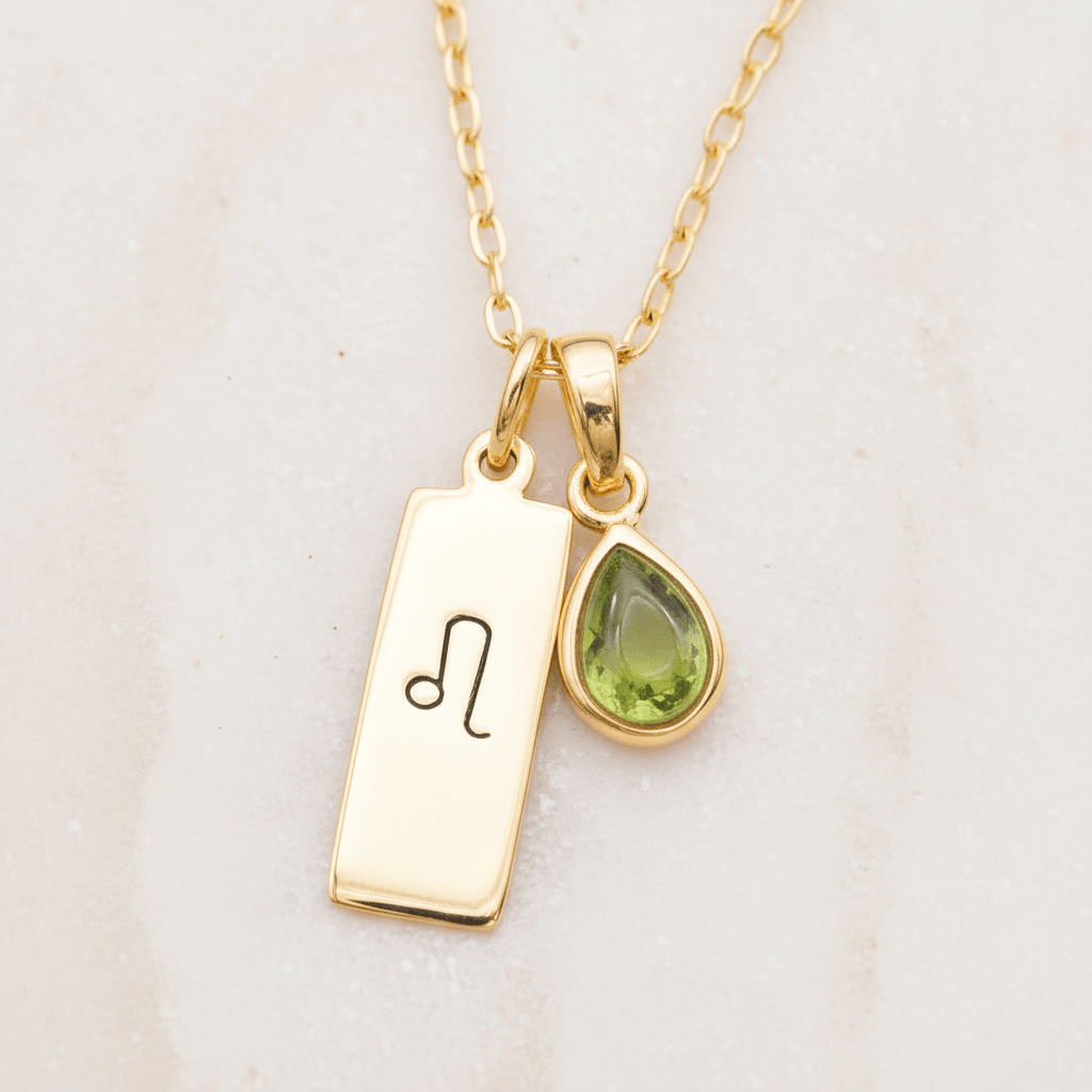 Gold necklace with a tag and a teardrop-shaped pendant on a light background