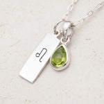 sterling silver Necklace with a leo zodiac pendant and a august birthstone peridot pendant on a light background