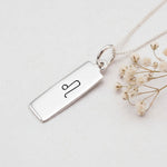 sterling silver leo zodiac necklace on a white background with dried babys breath