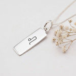 sterling Silver necklace with a pendant featuring a hand drawn leo zodiac symbol on a light background