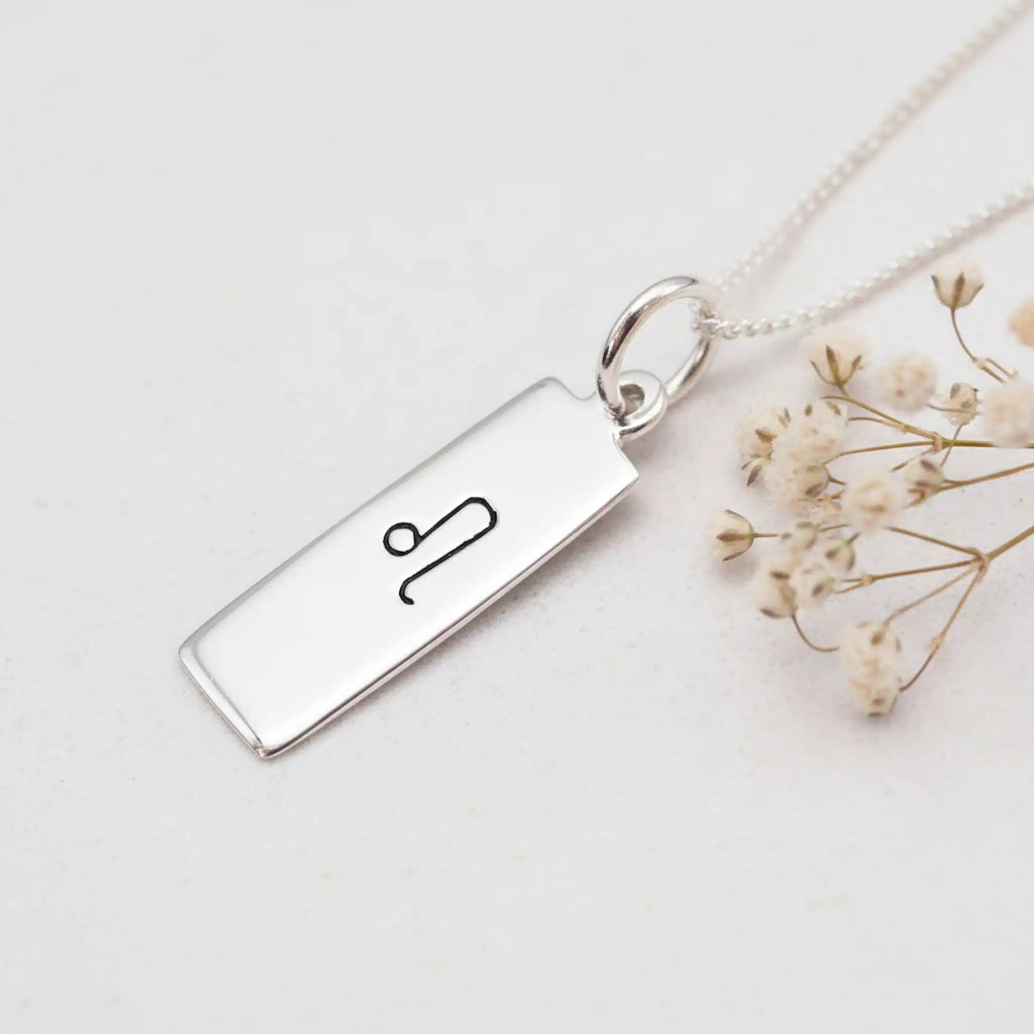 sterling Silver necklace with a pendant featuring a hand drawn leo zodiac symbol on a light background